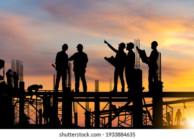 Silhouette of Engineer and worker on building site, construction site at sunset in evening time.