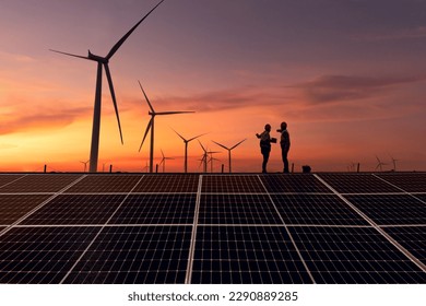 Silhouette engineer working on solar cell plant with windmill field .Solar cell smart grid and windmill are ecology energy renewable sunlight alternative green power environment factory concep.t
