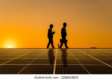 Silhouette engineers walking on roof inspect and check solar cell panel by hold equipment box ,radio communication, solar cell is smart grid ecology energy sunlight alternative power factory concept. - Shutterstock ID 2208424853