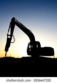 Silhouette of excavator in the oilfield at sunset selective focus