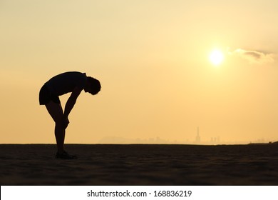 Silhouette of an exhausted sportsman at sunset with the horizon in the background