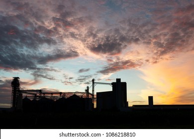 Silhouette factory and storage tanks raw material agricultural crops feed mills at twilight