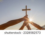 Silhouette family hands praying and holding Christian cross for worshipping God on mountain at sunrise background. Christian, Christianity, Religion copy space background. Easter Sunday concept: