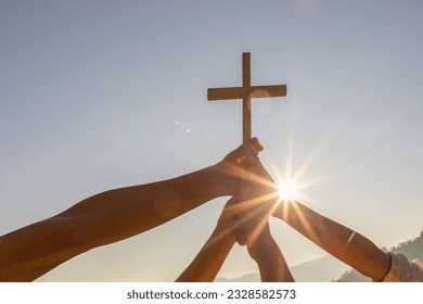 Silhouette family hands praying and holding Christian cross for worshipping God on mountain at sunrise background. Christian, Christianity, Religion copy space background. Easter Sunday concept: