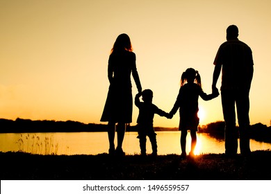 Familie Silhouette, einschließlich Vater, Mutter und zwei Kinder in den Händen der