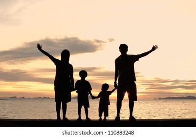 Silhouette Of Family On The Beach At Dusk.