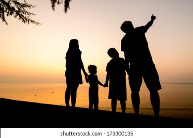 Silhouette Of Family On The Beach At Dusk.