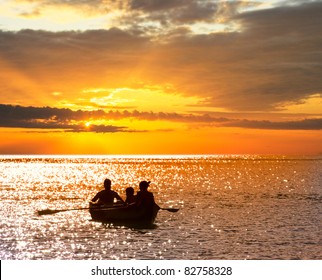 Silhouette Of A Family That Travels On A Boat At Sunset.