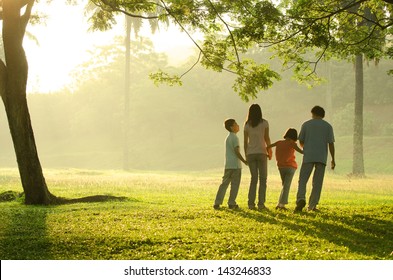 Silhouette Of A Family Walking In The Park During A Beautiful Sunrise, Backlight