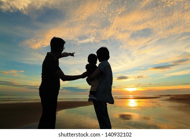 Silhouette Of Family Watching The Sunrise On The Beach