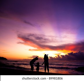 The Silhouette Of  Family Watching The Sunrise On The Beach