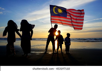 Silhouette Of Family With Waving A Malaysian Flag At Beach. Independence Day / Merdeka Day.