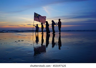 Silhouette Of Family With Waving A Malaysian Flag At Beach. Independence Day / Merdeka Day.