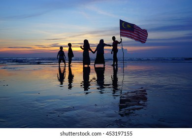 Silhouette Of Family With Waving A Malaysian Flag At Beach. Independence Day / Merdeka Day.