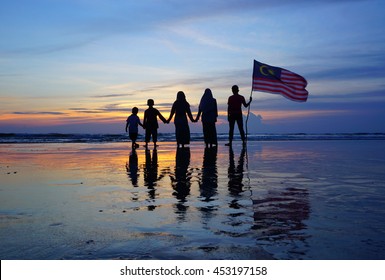 Silhouette Of Family With Waving A Malaysian Flag At Beach. Independence Day / Merdeka Day.