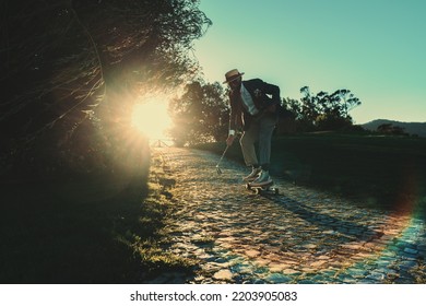 A Silhouette Of A Fancy Funny Black Guy In A Midlife Crisis Wearing An Elegant Suit With A Straw Hat And Sunglasses, Riding A Longboard On A Paving Stone On A Sunset With A Golf Club In His Hand