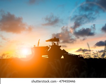 silhouette Farmer in tractor preparing land with seedbed cultivator over Blurred Agriculture