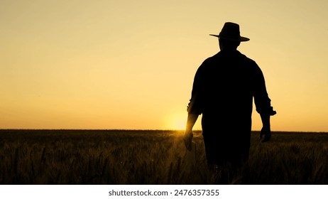 Silhouette Farmer walking with tablet in wheat field at sunset. Farmer works with digital tablet examines harvest of wheat in wheat field. Senior farmer analyzes grain harvest. Agricultural business - Powered by Shutterstock