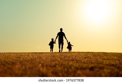 silhouette of father and children holding hands walking outdoors in the park. Fatherhood, and Father's Day concept.  - Powered by Shutterstock