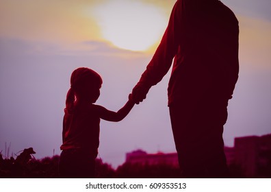 Silhouette Of Father And Daughter Holding Hands At Sunset