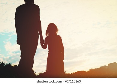 Silhouette Of Father And Daughter Holding Hands At Sunset