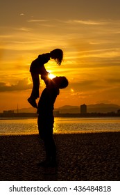 Silhouette Of Father And Daughter On The Beach