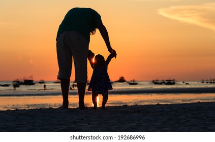 Silhouette Of Father And Little Daughter On Sunset Beach