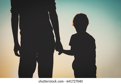 Silhouette Of Father And Son Holding Hands At Sunset