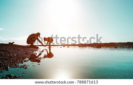 Silhouette of father and son playing on the beach at the sunset time - People having fun on summer vacation with their dog - Love, fatherhood and family concept