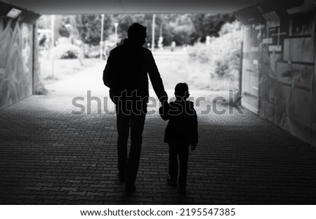 silhouette of father son walking his son child down a city street 