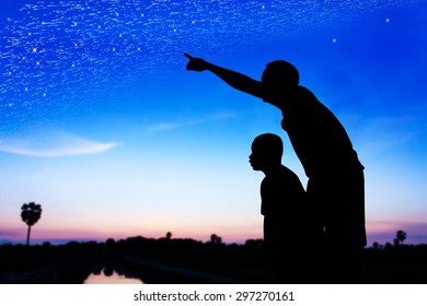 Silhouette of father use hand point his son look at meteor shower and star on the sky