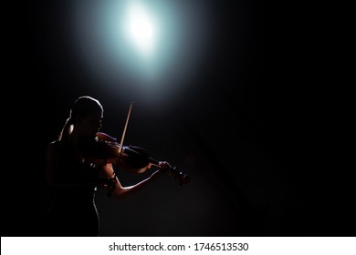 Silhouette Of Female Musician Playing On Violin On Dark Stage With Back Light