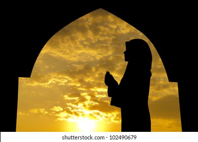 Silhouette Of Female Muslim Praying In Mosque During Sunset Time
