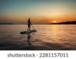 Silhouette of a female on the paddle boat at the sunset with copy space