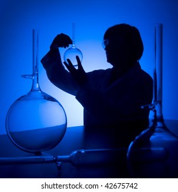 Silhouette Of Female Scientist Looking At Glass Flask