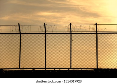 Silhouette of fence with barbed wire.