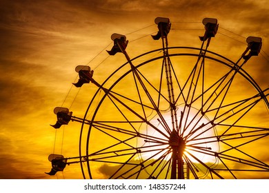 Silhouette of ferris wheel at sunset during summer at county fair