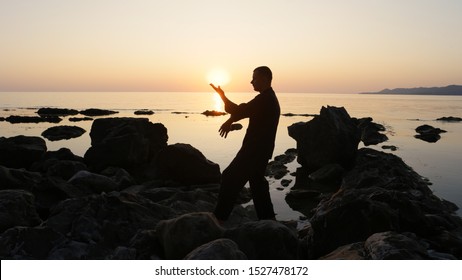 Silhouette of a fighter Wing Chun on a background of sea sunset. on the stones. sun and hand. combat stance. close-up. Tan sao bong sao - Powered by Shutterstock