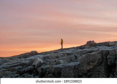 A silhouette, a figure on a steep cliff against the background of the sunset dark sky. - Powered by Shutterstock