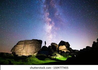 Silhouette Of Figure Stargazing In Rocky Landscape Below A Clear Night Sky & Vibrant Milky Way, Dartmoor National Park, UK