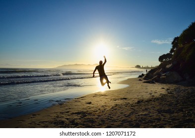 Silhouette Figure In The Sunrise On Beach In Front Of Ocean In Byron Bay, Australia.