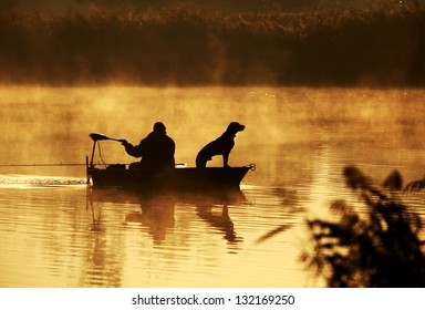 Silhouette of fisher and dog sitting in boat