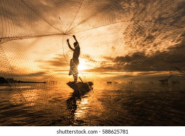 Silhouette Fisherman Fishing Nets on the boat.Thailand