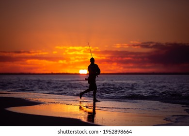 A Silhouette Of A Fisherman Fishing At Rainbow Beach, Queensland, Australia, At Sunset.