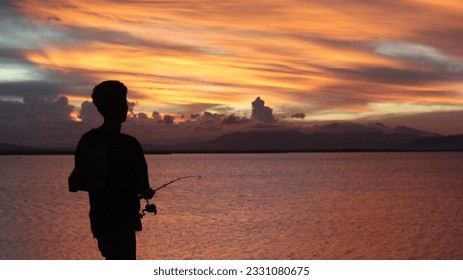 silhouette of a fisherman with a fishing rod in the lake at sunset
 - Powered by Shutterstock