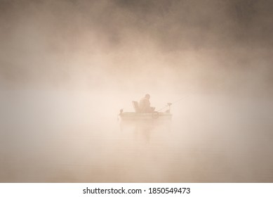 Silhouette of a fisherman in a rafting boat in thick fog. - Powered by Shutterstock