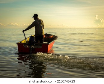 Silhouette of a fishermen on boat with outboard motor boat ready to fishing during beautiful sunrise at Labuan island, Malaysia. - Powered by Shutterstock