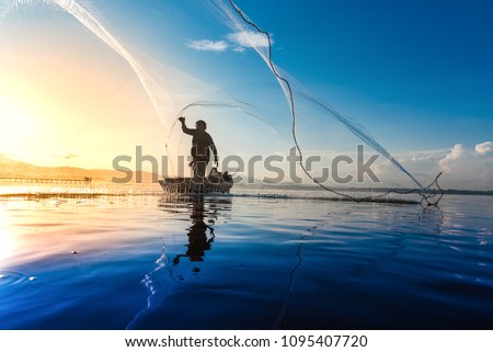 Silhouette of fishermen using coop-like trap catching fish in lake with beautiful scenery of nature morning sunrise. Beautiful scenery at Bang-Pra, Chonburi Province Thailand.