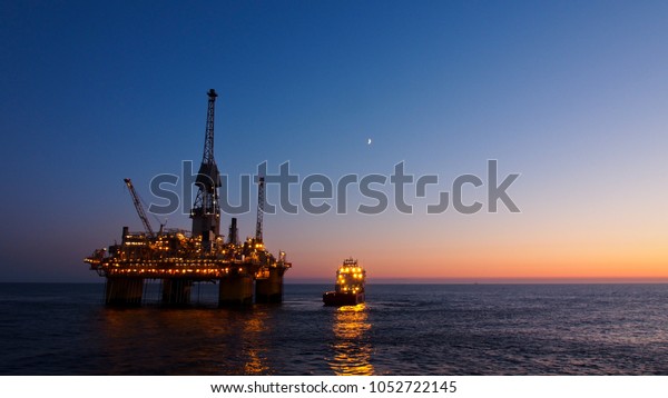 Silhouette of a floating production\
platform in North Sea region, Norway with sunset as\
background.
