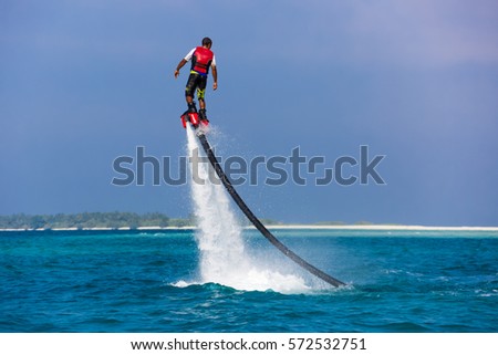 Silhouette of a fly board rider at blue sea blue sky. Professional rider do tricks in the blue lagoon. Summer water-sport equipment.